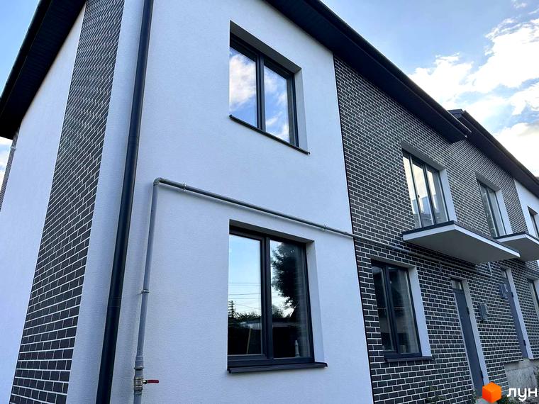 Новобудова на вул. Стадникової, 41 з комбінованим фасадом: біла штукатурка та темно-сіра цегляна кладка, вікна з темними рамами.