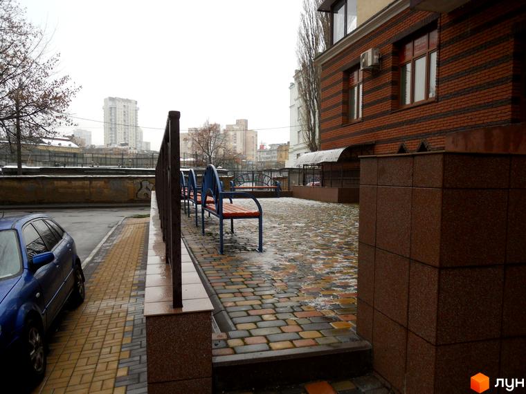 Зовнішній вигляд будинку на вул. Коперника, 11, з прибудинковою територією та лавками для відпочинку.