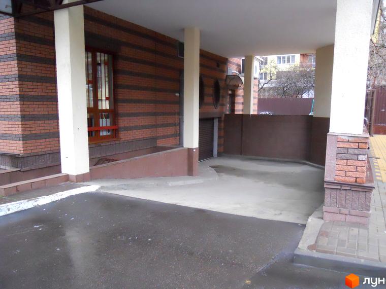 Житловий комплекс на вул. Коперника, 11. Вхідна група з цегляною облицовкою та навісом. Прибудинкова територія з асфальтованим покриттям.