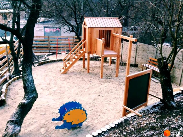 Дитячий майданчик з дерев'яним будиночком та гіркою в прибудинковій території житлового комплексу ЖК Віконт.