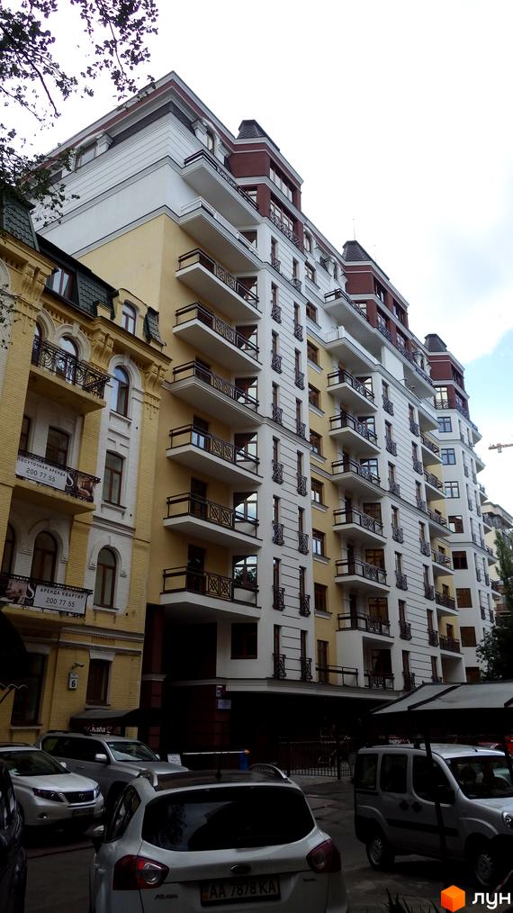 ARCH House - новий житловий комплекс з білими фасадами та балконами. Поруч розташовані жовті будинки та припарковані автомобілі.