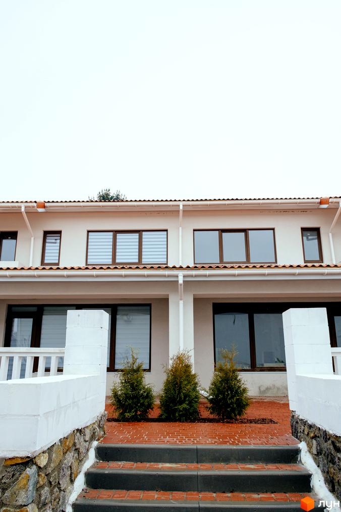 Зовнішній вигляд будинку КМ Little Italy Apartments з вікнами та дахом, прибудинкова територія з деревами та сходами.