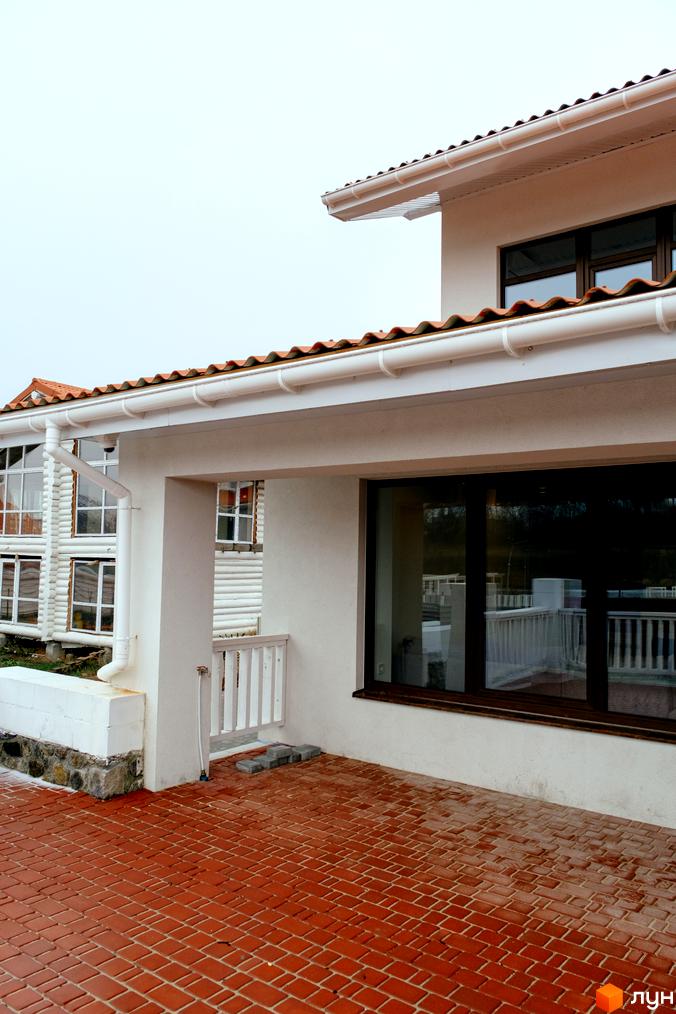 Котеджне містечко КМ Little Italy Apartments. Зовнішній вигляд будинку з червоною черепицею та великими вікнами, прибудинкова територія з бруківки.