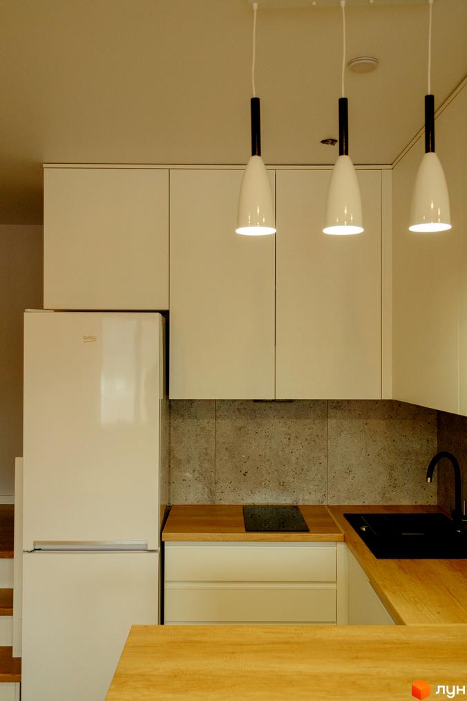 Інтер'єр кухні в новобудові КМ Little Italy Apartments з білими фасадами, дерев'яною стільницею та підвісними світильниками.