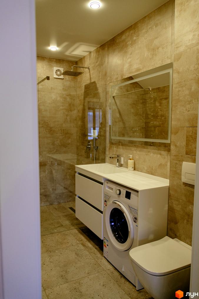 Сучасний дизайн ванної кімнати з душовою кабіною, пральною машиною та туалетом. Стильні світлі плитки на стінах та підлозі.