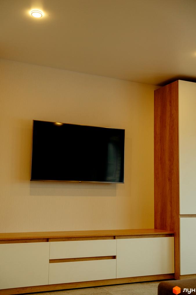 Вітальня з телевізором та тумбою в КМ Little Italy Apartments. Сучасний дизайн інтер'єру з дерев'яними елементами.