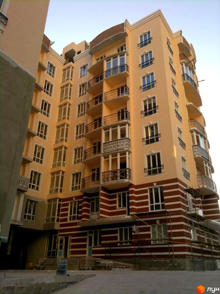 Житловий комплекс Посольський. Зовнішній вигляд багатоповерхового будинку з балконами та вікнами. Навколо будинку будівельні роботи та матеріали.