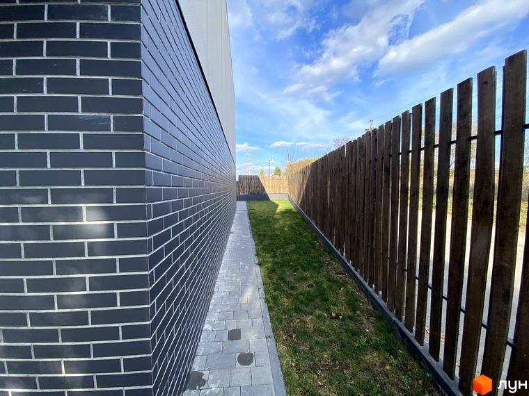 Таунхаус Новоолександрівський: сучасна цегляна стіна та дерев'яний паркан з зеленою галявиною. Зовнішній вигляд будинку та прибудинкової території.