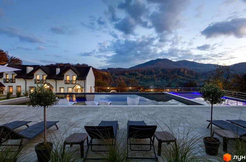 Фото Apartel Shayan Villas з басейном та лежаками на терасі. На фоні видно гори та ліс.