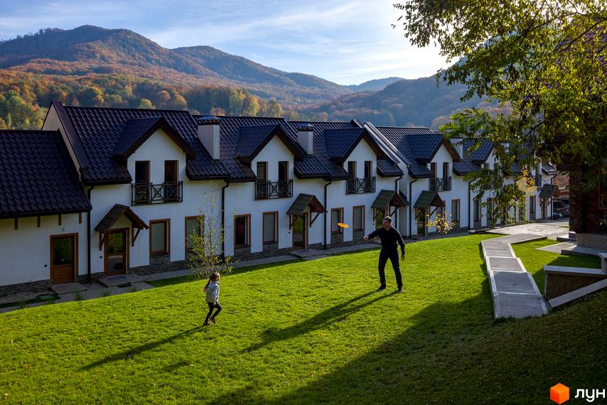 Apartel Shayan Villas - житловий комплекс з білими фасадами та темними дахами, розташований на тлі гір. На прибудинковій території зелений газон та доріжки.