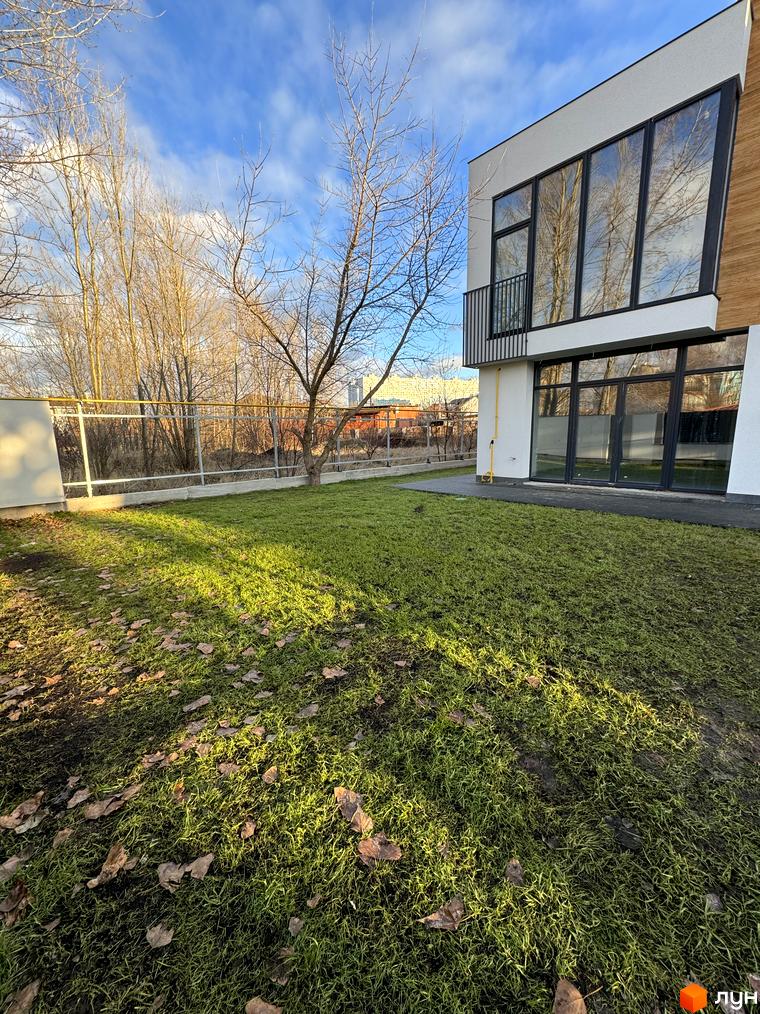 Зображення таунхауса в Gatne Country Club. На передньому плані газон з опалим листям.