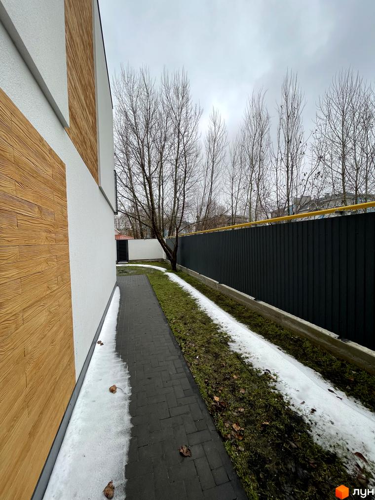 Таунхауси Gatne Country Club: біла стіна з дерев'яними вставками, доріжка з бруківки та зелена територія з деревами.