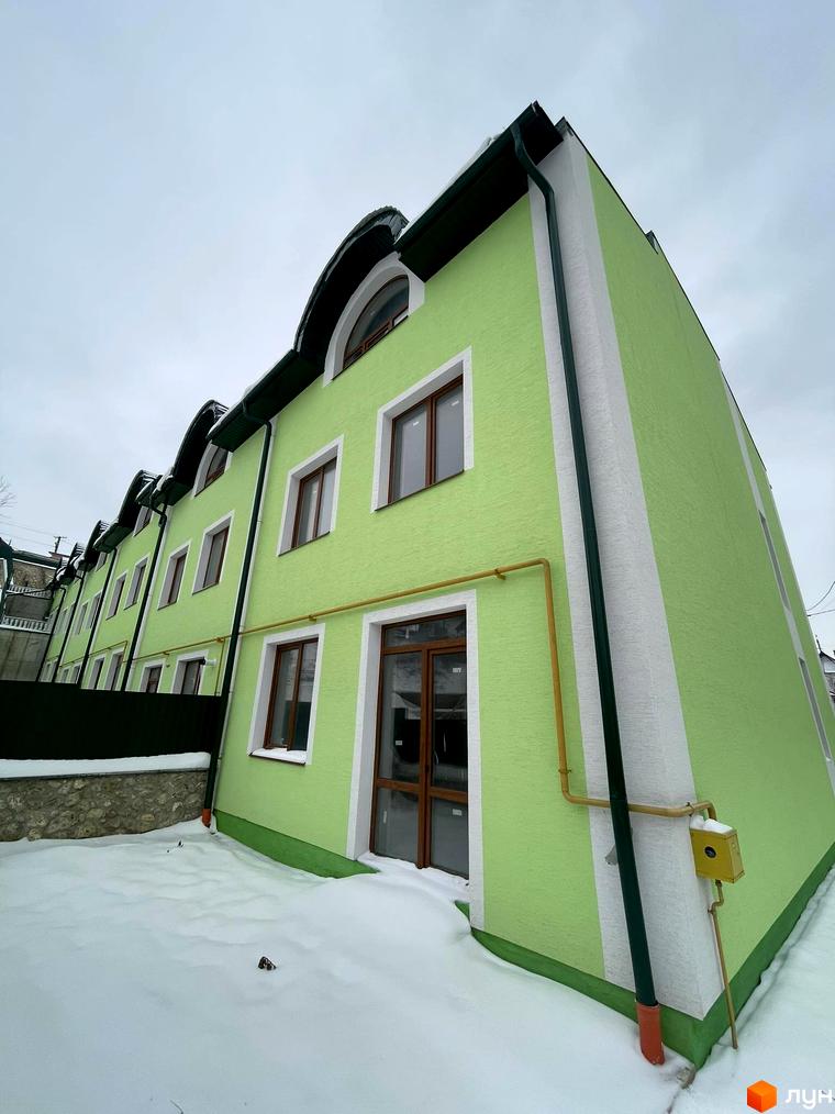 Зовнішній вигляд таунхаусів „Гаї Гречинські“ взимку, зелені фасади, білі декоративні елементи, вікна, двері, засніжена прибудинкова територія.