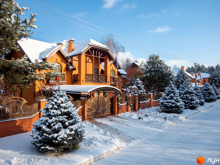 Котеджне містечко Парк хаус. Цегляні будинки з білими дахами, вкритими снігом, та зелені ялинки. Прибудинкова територія засніжена, з доглянутими деревами та парканом.