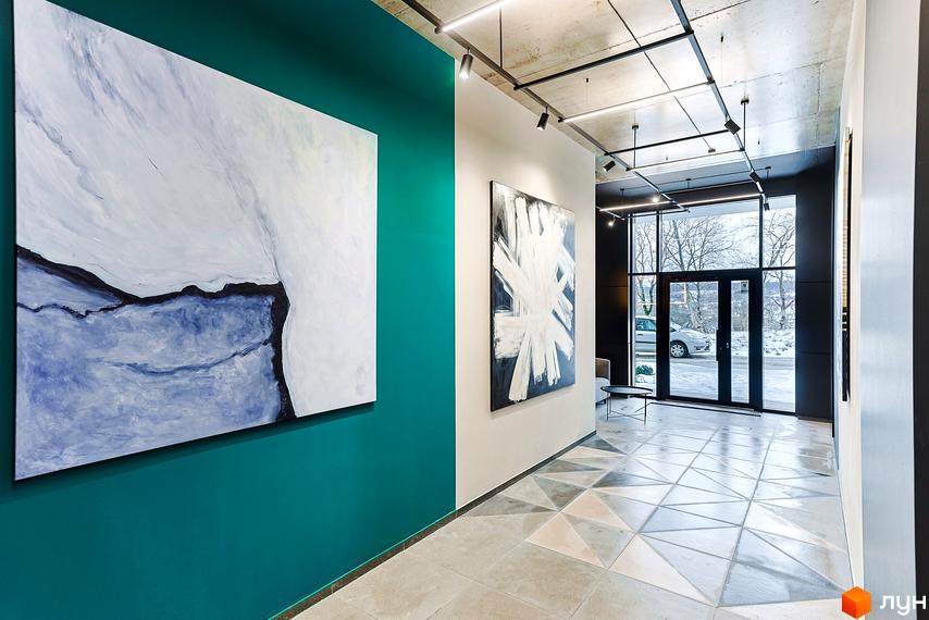 Просторий хол Житлового комплексу ARTHOUSE park з яскравою акцентною стіною, абстрактними картинами та візерунковою підлогою.