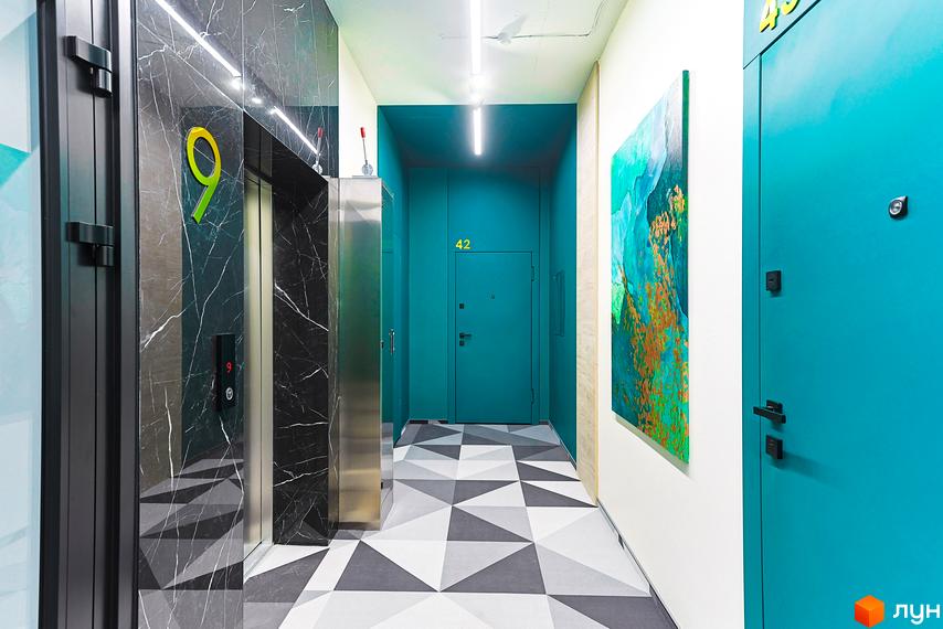 Інтер'єр Житлового комплексу ARTHOUSE park: хол з ліфтом, оздобленим чорним мармуром, та бірюзовими дверима квартир.