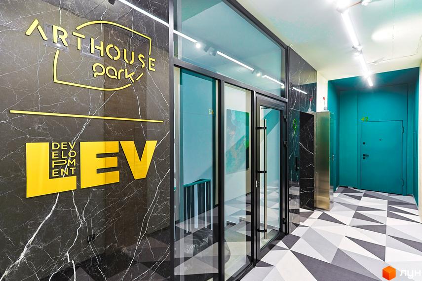 Вхідна група Житловий комплекс ARTHOUSE park з мармуровим оздобленням, скляними дверима та геометричним дизайном підлоги. Яскрава вивіска з назвою комплексу.