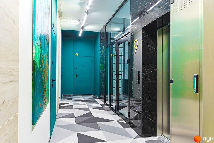 Коридор в ЖК ARTHOUSE park з ліфтом, оздоблений чорним мармуром, та дверима з геометричним візерунком на підлозі. Яскравий дизайн інтер'єру.