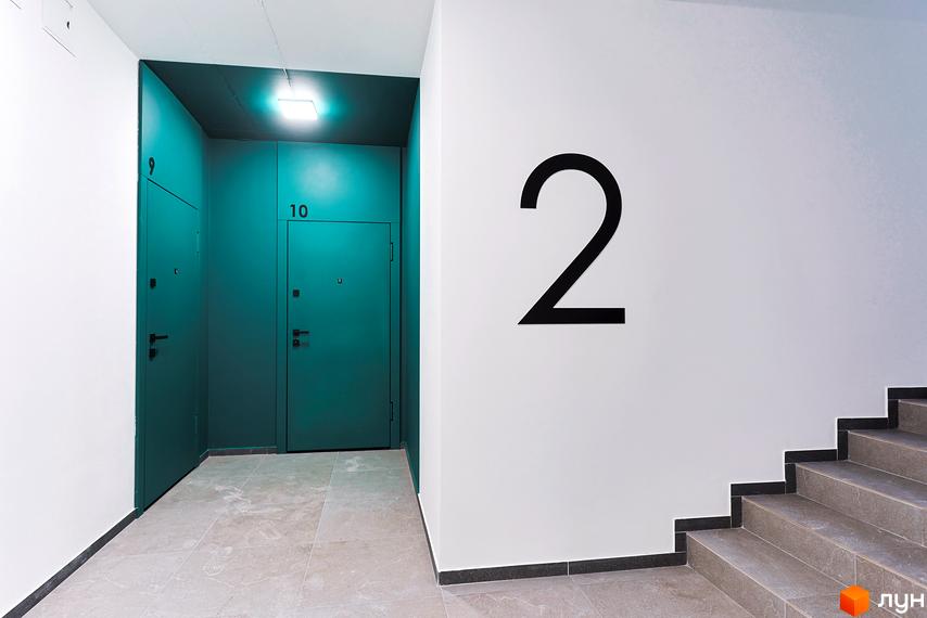 Коридор житлового комплексу ARTHOUSE park з дверима та сходами. На стіні велика цифра 2.