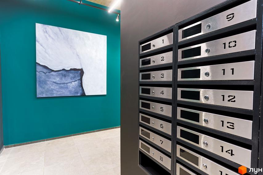 Поштові скриньки та абстрактна картина з пейзажем на бірюзовій стіні у холі Житлового комплексу ARTHOUSE park.