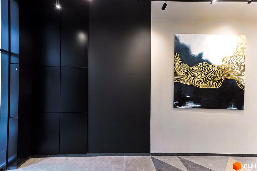 Чорні панелі на стіні в ЖК ARTHOUSE park. На стіні висить картина з золотими лініями на темному фоні, що додає елегантності інтер'єру.