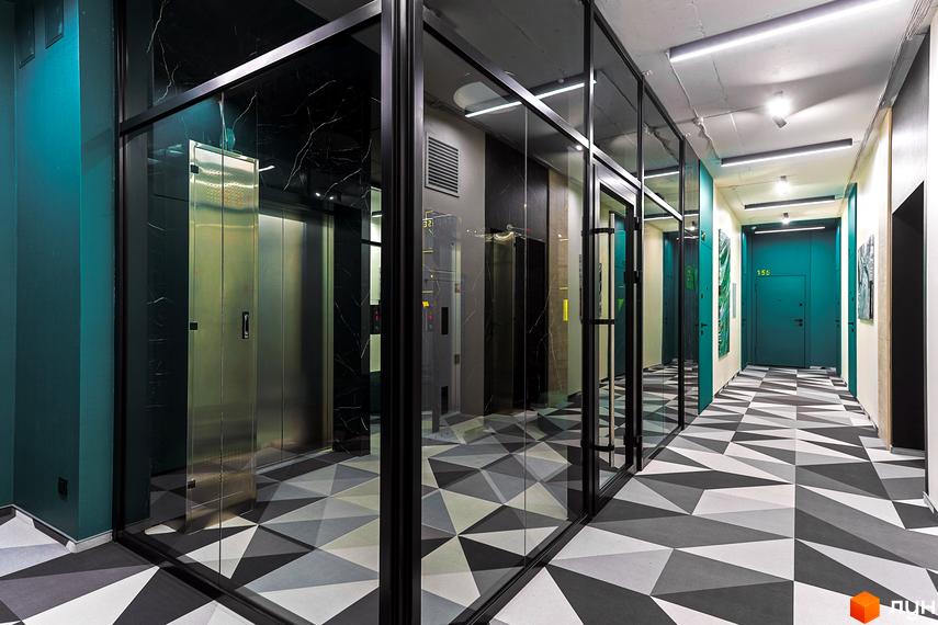 Інтер'єр спільного коридору Житлового комплексу ARTHOUSE park з бірюзовими стінами, скляними перегородками та геометричною підлогою.