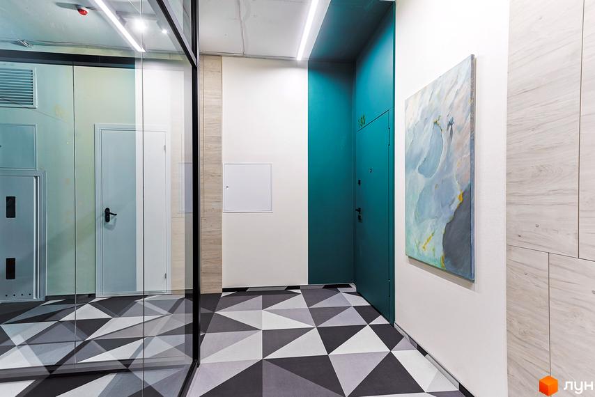 Коридор Житлового комплексу ARTHOUSE park з геометричним візерунком на підлозі та дзеркалом. Стіни оформлені білим кольором та бірюзовою акцентною стіною.