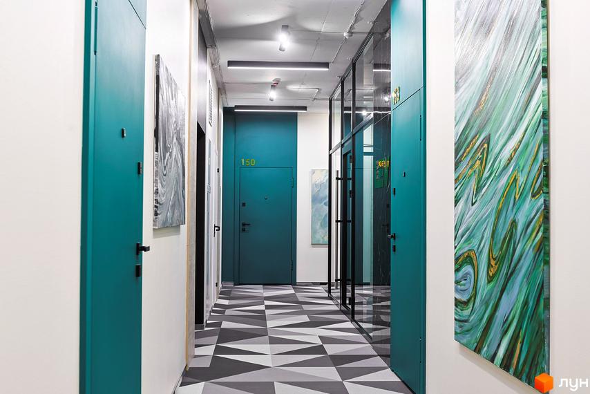 Коридор в ЖК ARTHOUSE park з дверима бірюзового кольору, картинами та геометричною підлогою. Вид на вхідну зону.