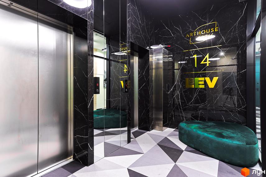 Вхідна група Житлового комплексу ARTHOUSE park з чорними мармуровими стінами, дзеркалами та ліфтами. На підлозі геометричний візерунок, а на стіні вказано 14 поверх та логотип.