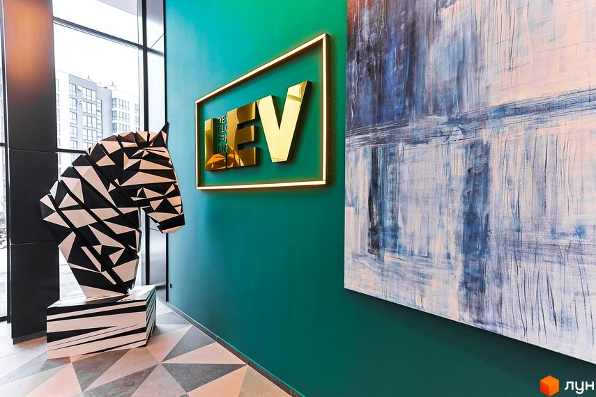 Інтер'єр ЖК ARTHOUSE park: холл з геометричною скульптурою коня, золотим логотипом забудовника та абстрактним живописом на стінах.