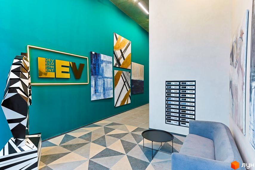 Інтер'єр холу житлового комплексу ARTHOUSE park: бірюзові стіни, золотий логотип, абстрактні картини та геометрична підлога.