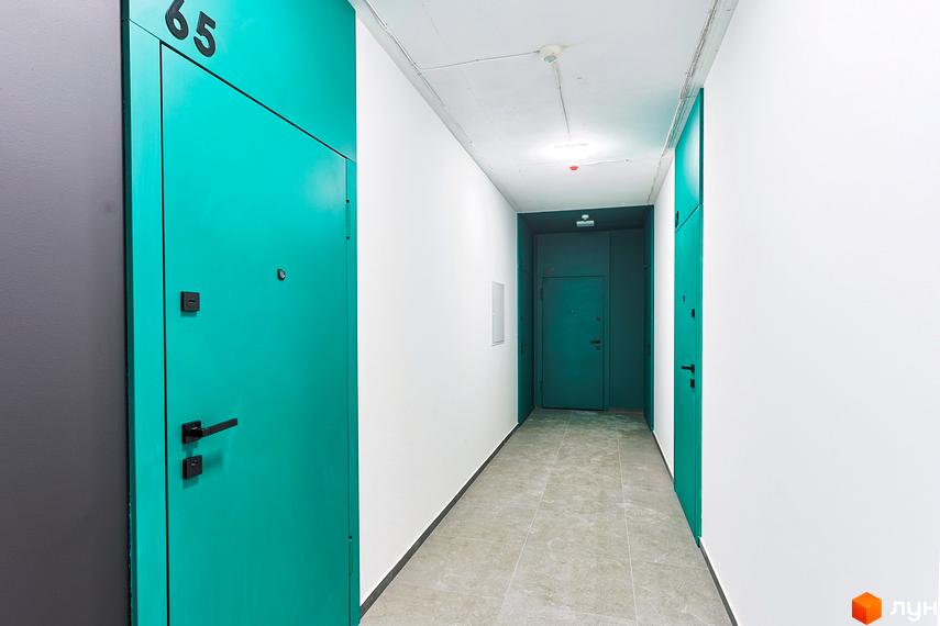 Коридор в ЖК ARTHOUSE park з бірюзовими дверима. На стінах біла фарба, на підлозі плитка. Видно двері в кінці коридору.