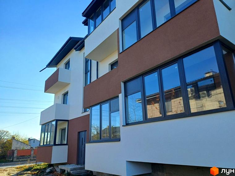 Житловий комплекс Тарас Шевченко з білим та теракотовим фасадом, великими вікнами. Поруч дорога та прибудинкова територія.