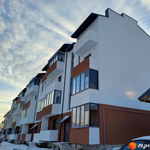 Житловий комплекс Тарас Шевченко: ряд білих багатоповерхових будинків з коричневими елементами та заскленими балконами. Навколо будинків видно сніг.