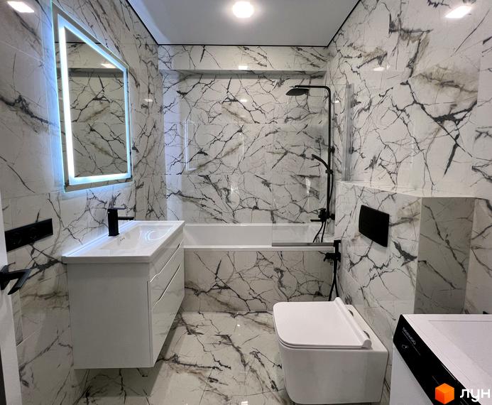 Сучасний дизайн ванної кімнати у білих тонах з мармуровим оздобленням та підсвіченим дзеркалом. Стильна сантехніка та душова система створюють комфорт.