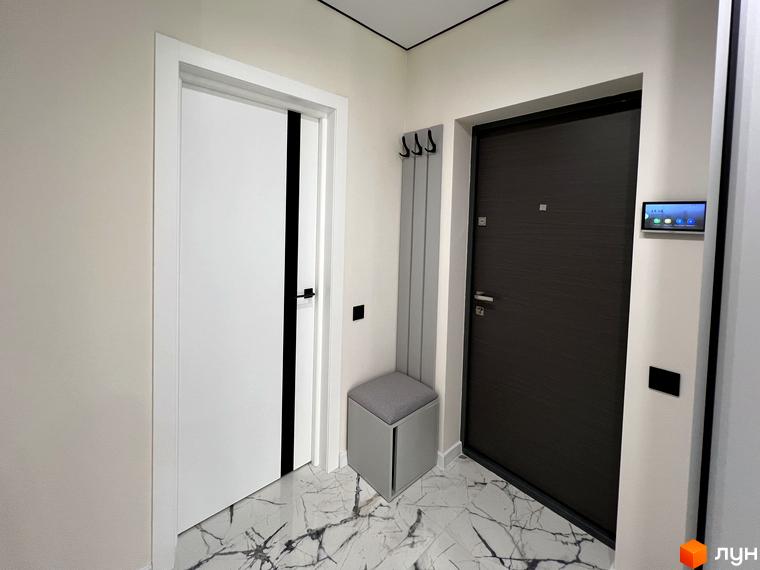 Передпокій з двома дверима, сірою лавою та панеллю керування. Клубний будинок „Васильченка“ – ваш новий дім.