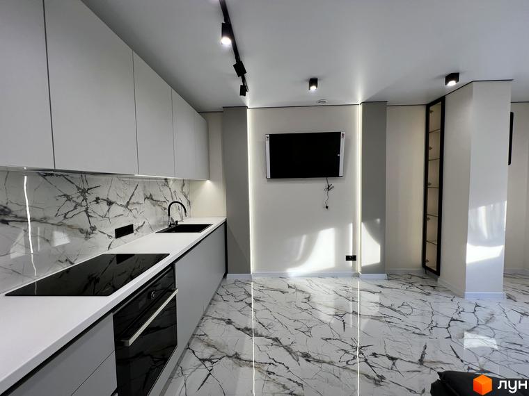 Інтер'єр кухні в клубному будинку Васильченка з білими фасадами, мармуровим фартухом та сучасною технікою. Простора вітальня з телевізором та підсвіткою.
