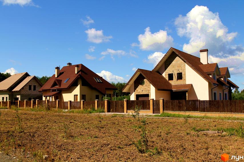 Котеджне містечко Лелечий Хутір. Двоповерхові будинки з коричневими дахами та парканом. Поруч знаходиться прибудинкова територія з сухою травою.