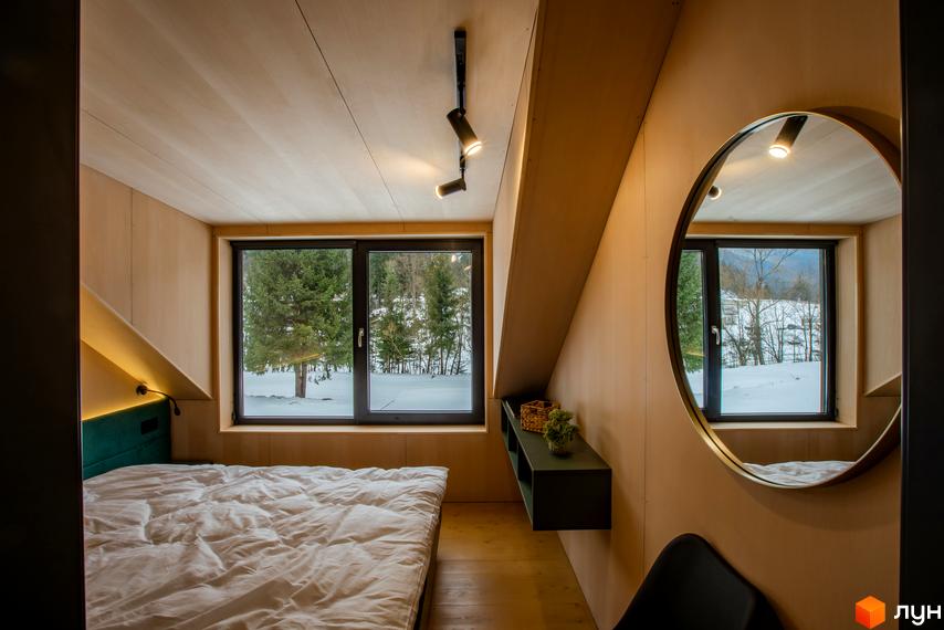 Затишна спальня з великим вікном, що виходить на зимовий ліс. Дизайн інтер'єру в стилі мінімалізм з дерев'яними елементами.