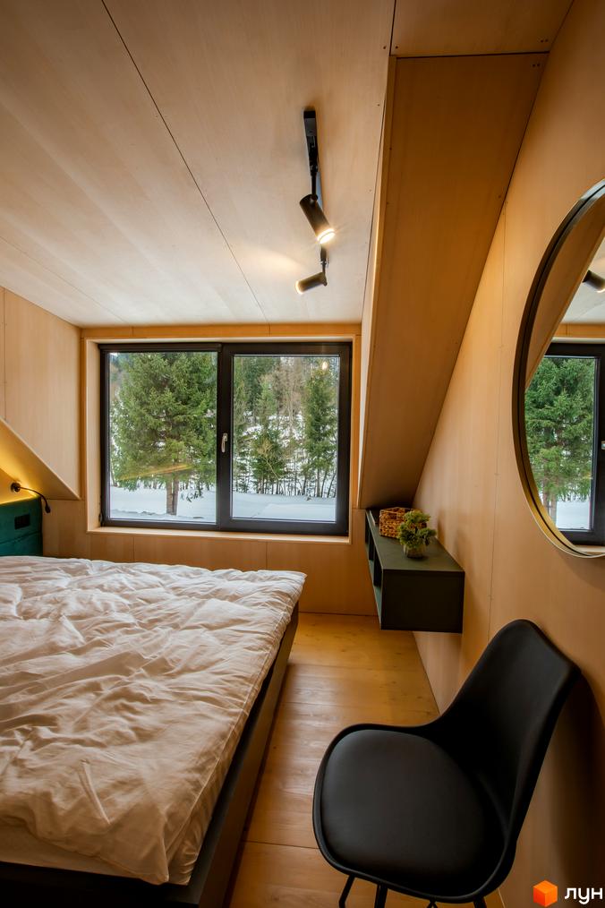 Інтер'єр спальні в котеджному містечку КМ TYSHA з панорамним вікном та видом на зимовий ліс. Затишна атмосфера для відпочинку.