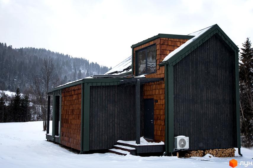 Котеджне містечко TYSHA у Карпатах, з дерев'яною обшивкою та великими вікнами, розташоване серед засніжених дерев.