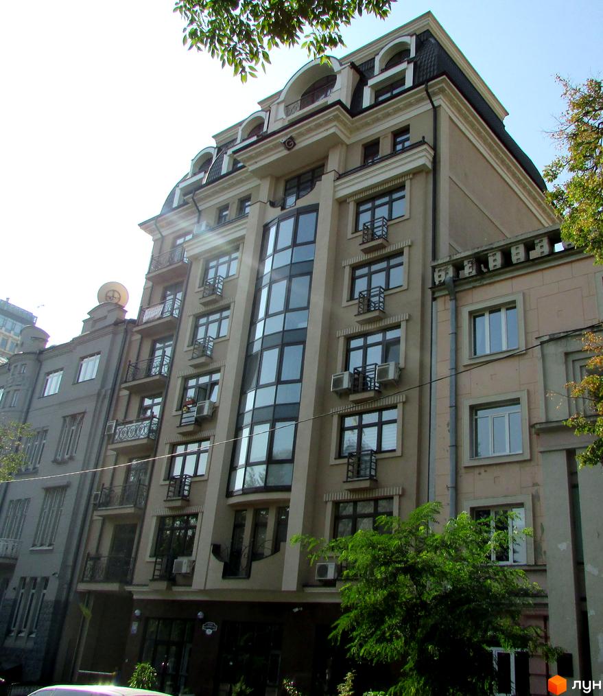 Фасад Житлового комплексу Botanic Paradise з мансардним дахом та великими вікнами. Навколо будинку видно зелені дерева.