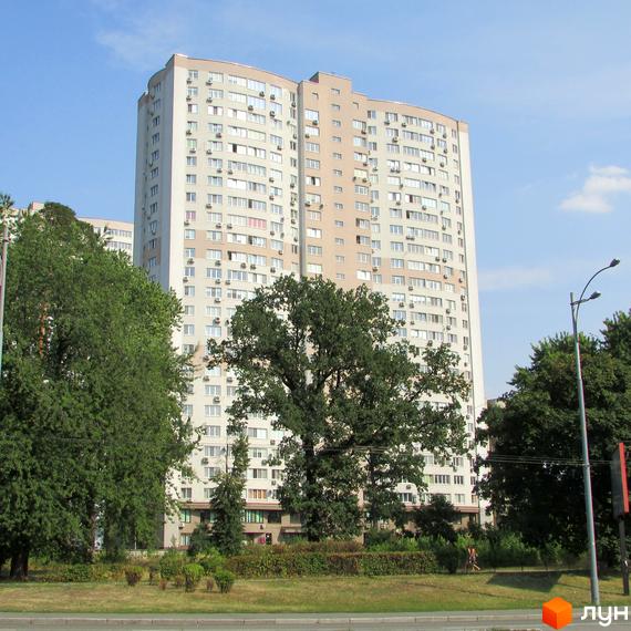 Житловий комплекс Вікторія: багатоповерховий будинок світлого кольору з численними вікнами, оточений зеленими деревами та доглянутою територією.