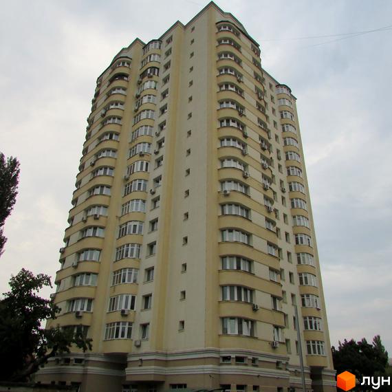 Багатоповерховий житловий будинок світло-жовтого кольору з численними балконами та вікнами. Житловий комплекс на вул. Гашека, 8а, оточений деревами.