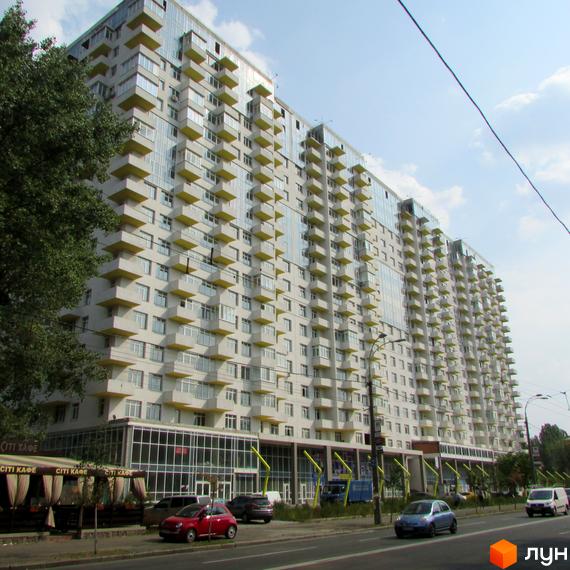 Житловий комплекс Перлина Нивок з балконами та великою прибудинковою територією. Вид на фасад будинку з парковкою та зеленими насадженнями.