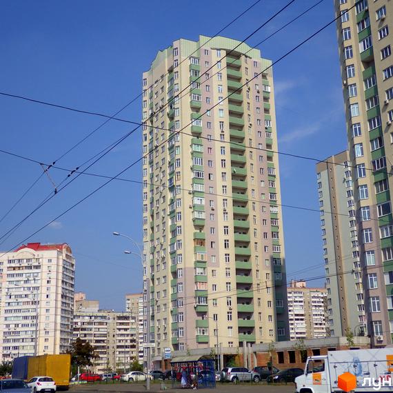 Житловий комплекс Троєщина з висотними будинками та прибудинковою територією, що включає зелені зони та парковки.