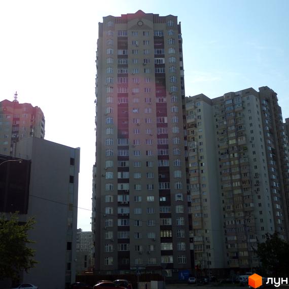 Вигляд житлового комплексу ЖК Троєщина з фасадом та прибудинковою територією, що включає зелені насадження.