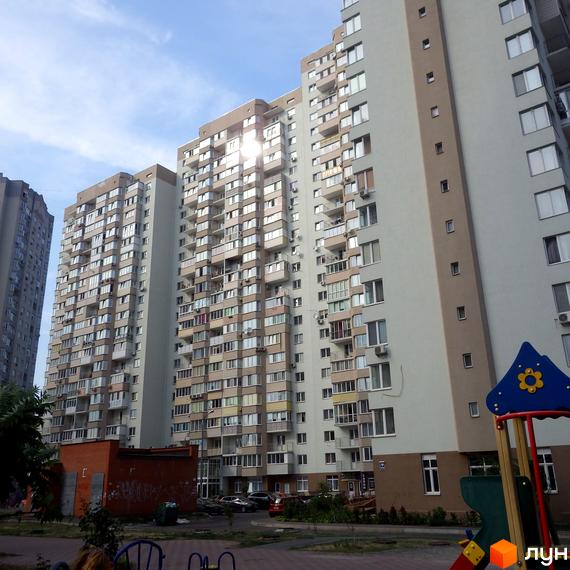 Житловий комплекс Троєщина з висотними будинками та прибудинковою територією, де розташовані дитячі майданчики.