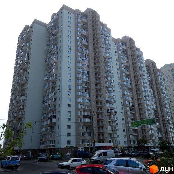 Житловий комплекс Троєщина з висотними будинками та прибудинковою територією, де розташовані автомобілі.