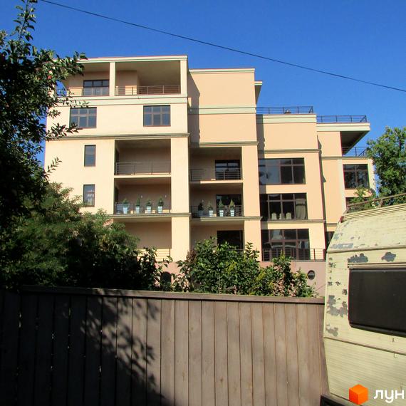 Житловий комплекс Jardan Le Roi з великими вікнами та балконами, оточений зеленими насадженнями та прибудинковою територією.